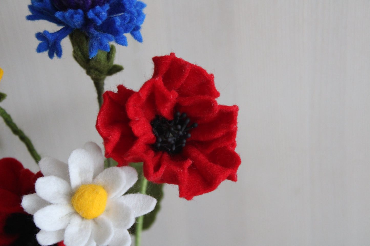 Close-up Vilten bloemen boeket als decoratie. Handgemaakte korenbloem, klaproos en margriet met een lichte achtergrond.