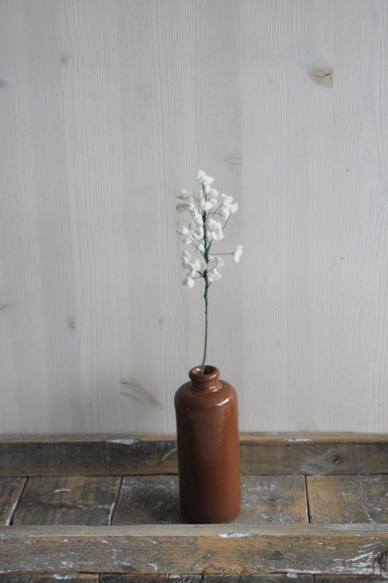 Viltbloemen gipskruid, perfect als duurzame decoratie of in een boeket, handgemaakt in een bruine vaas op een houten ondergrond en lichte achtergrond