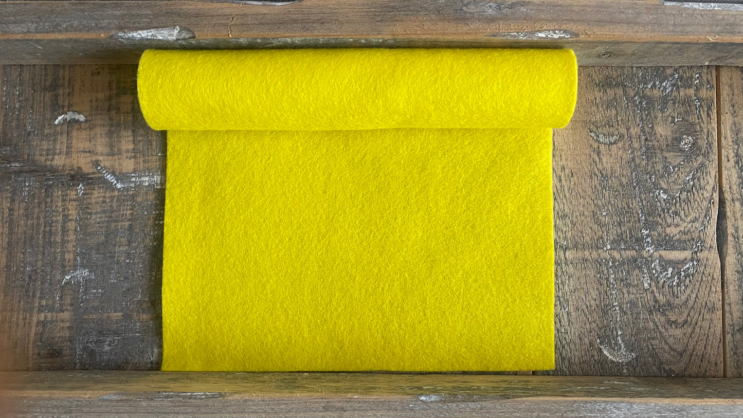 Rolletje geel wolvilt nummer 16 op een houten ondergrond