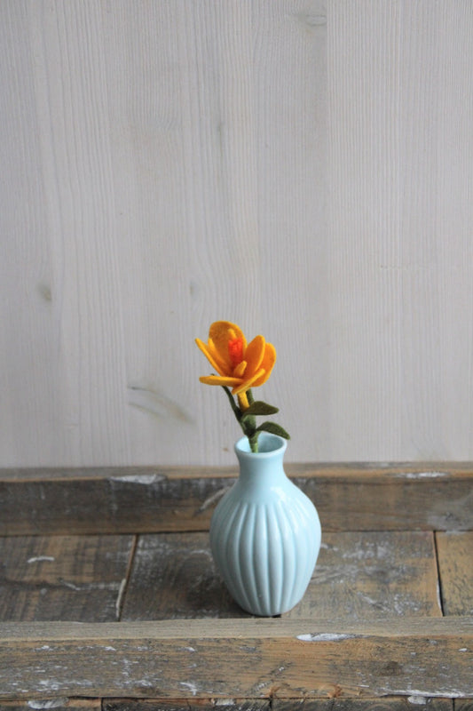 Vrolijke gele handgemaakte krokus in een blauw vaasje op een rustieke houten ondergrond