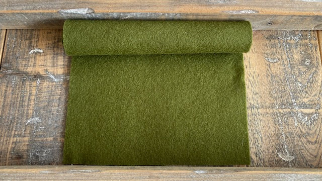 Rolletje wolvilt in de kleur bladgroen nummer 63 op een houten ondergrond voor het maken van viltbloemen, zoals vilten bladeren en blad