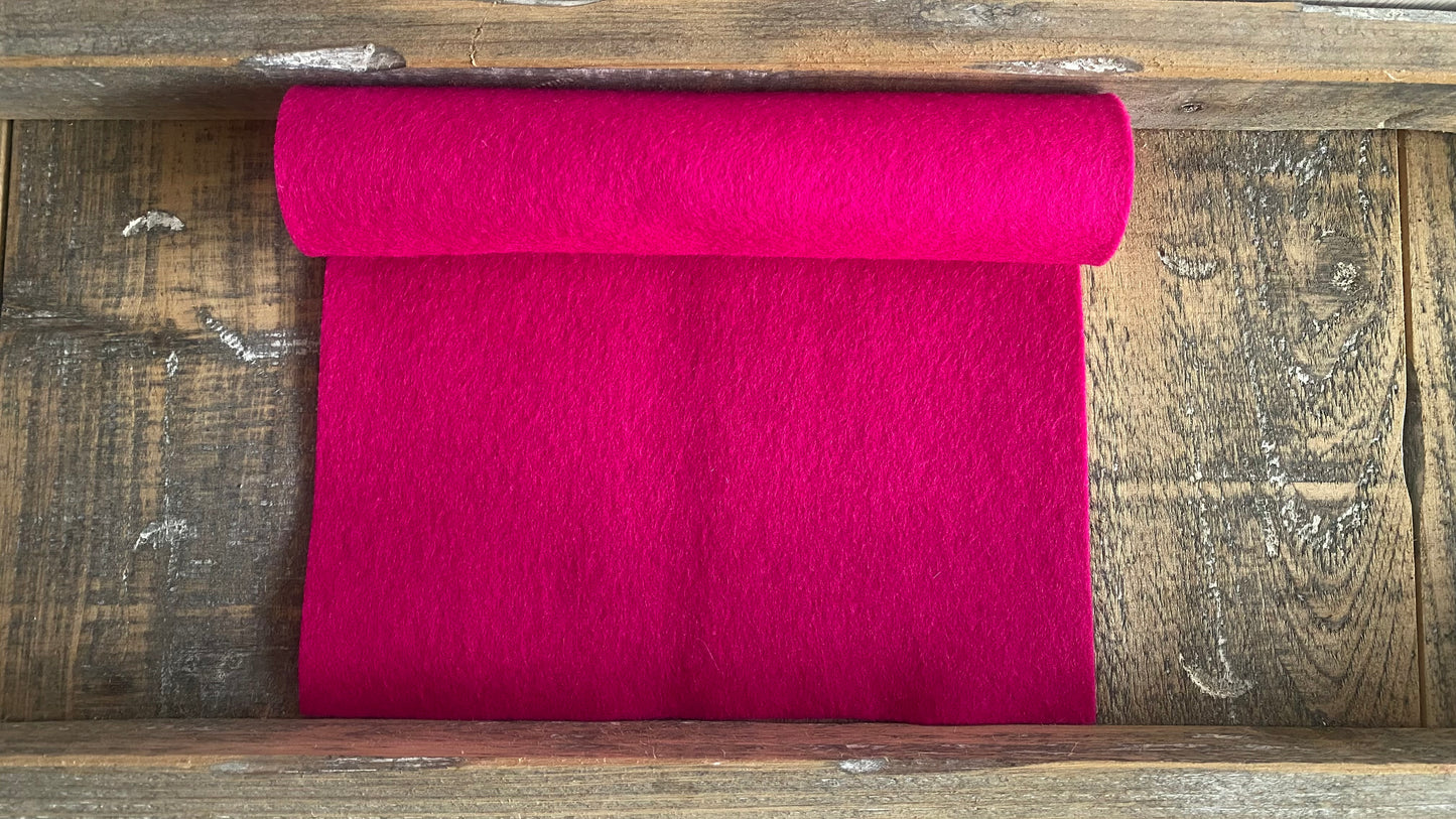 Rolletje wolvilt in de kleur donker fuchsia nummer 73 op een houten ondergrond voor het maken van viltbloemen, zoals vilten roos, vilten anemoon, vilten pioenroos, hortensia van vilt
