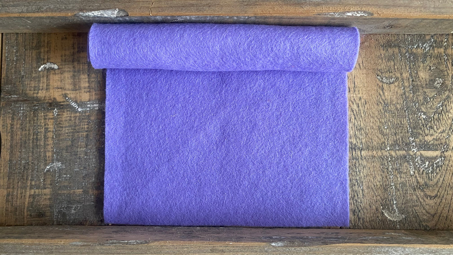 Rolletje wolvilt in de kleur blauw lila nummer 562 op een houten ondergrond voor het maken van viltbloemen, zoals vilten lavandel, vilten anemoon, vilten hybiscus, hortensia van vilt