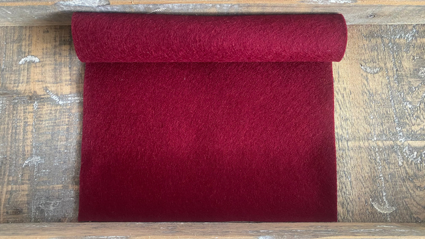 Rolletje wolvilt in de kleur bordeaux nummer op 10 een houten ondergrond voor het maken van viltbloemen, zoals vilten roos, vilten anemoon, vilten pioenroos, hortensia van vilt