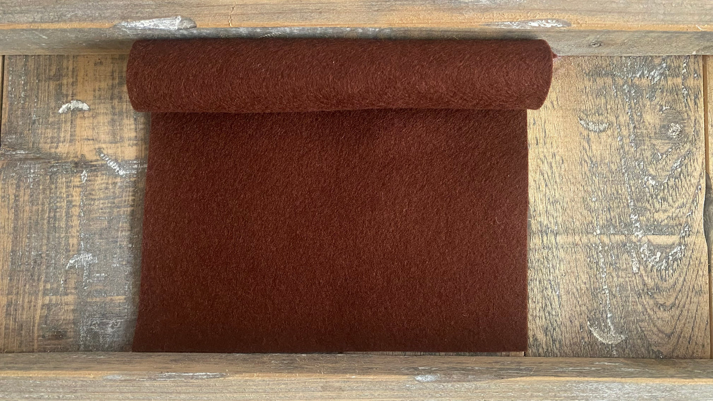 Rolletje wolvilt in de kleur bruin nummer 48 op een houten ondergrond voor het maken van viltbloemen, zoals vilten bladeren of vilten denneappels