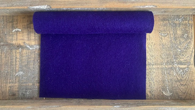 Rolletje wolvilt in de kleur donkerpaars nummer 76 op een houten ondergrond voor het maken van viltbloemen, zoals vilten anemoon, hortensia van vilt