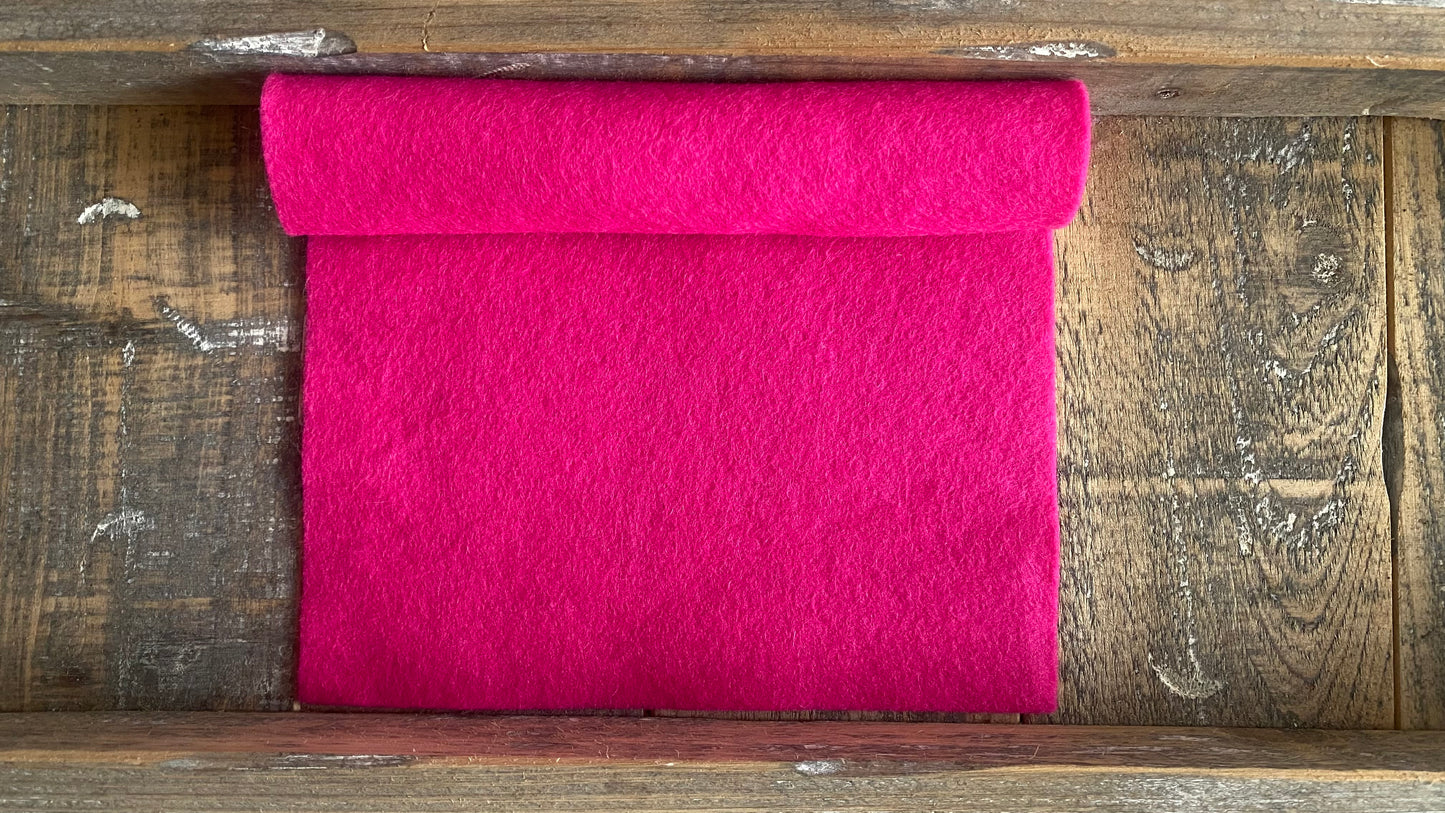 Rolletje wolvilt in de kleur fel roze op een houten ondergrond voor het maken van viltbloemen, zoals vilten roos, vilten anemoon, vilten pioenroos, hortensia van vilt