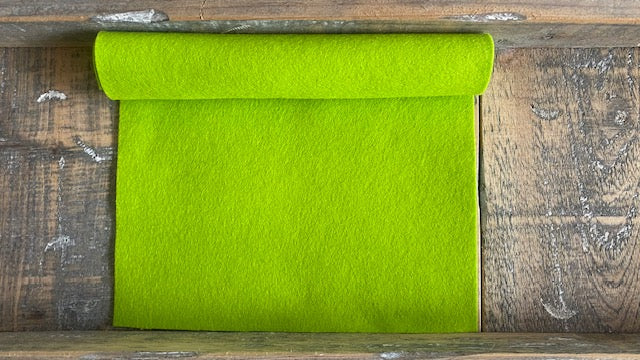 Rolletje wolvilt in de kleur lentegroen nummer 29 op een houten ondergrond voor het maken van viltbloemen