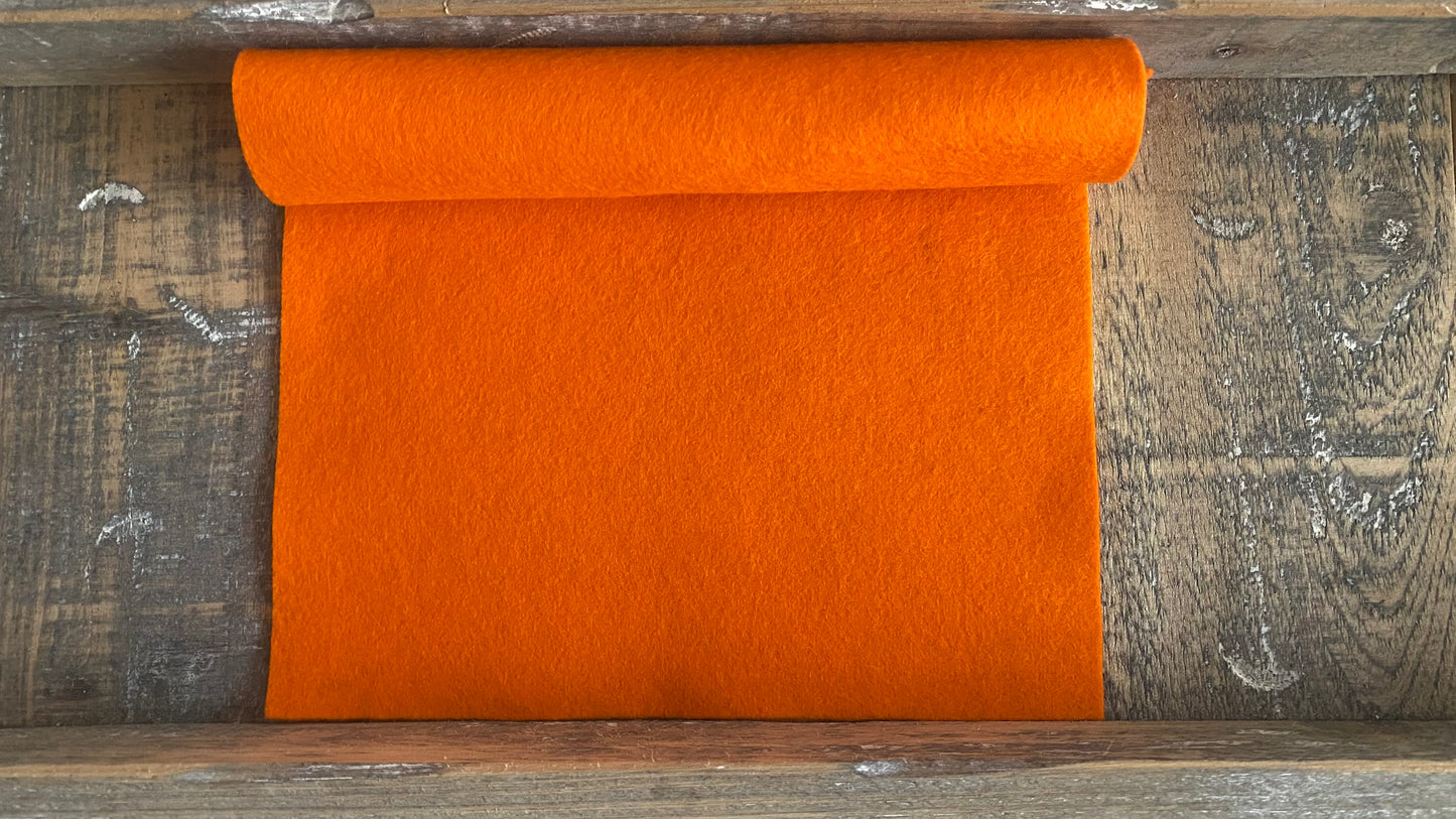 Rolletje wolvilt in de kleur licht oranje nummer 19 op een houten ondergrond voor het maken van viltbloemen, zoals vilten roos, vilten gerbera, vilten lampionnetje, slaapmutsje van vilt