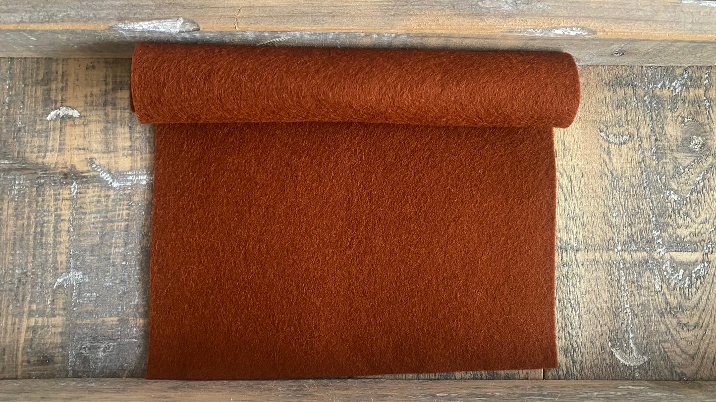 Rolletje wolvilt in de kleur midden bruin nummer 47 op een houten ondergrond voor het maken van viltbloemen, zoals vilten blad, denneappel van vilt