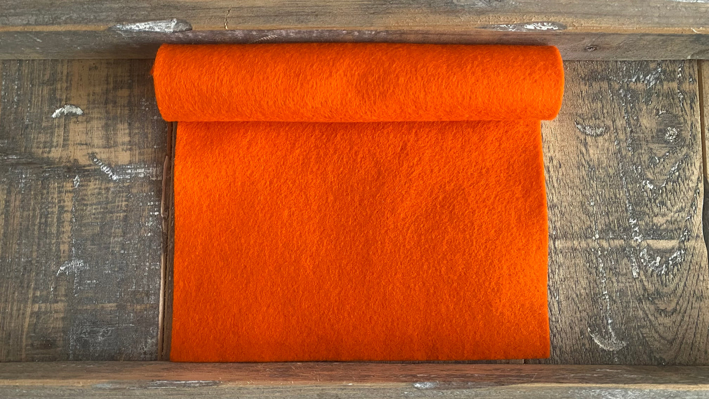 Rolletje wolvilt in de kleur oranje nummer 19 op een houten ondergrond voor het maken van viltbloemen, zoals vilten gerbera, vilten lampionnetjes