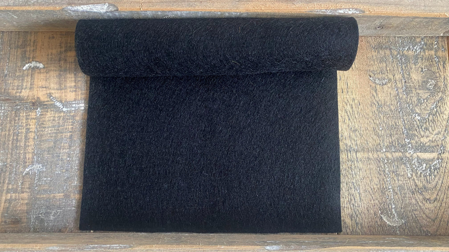 Rolletje wolvilt in de kleur zwart nummer 67 op een houten ondergrond