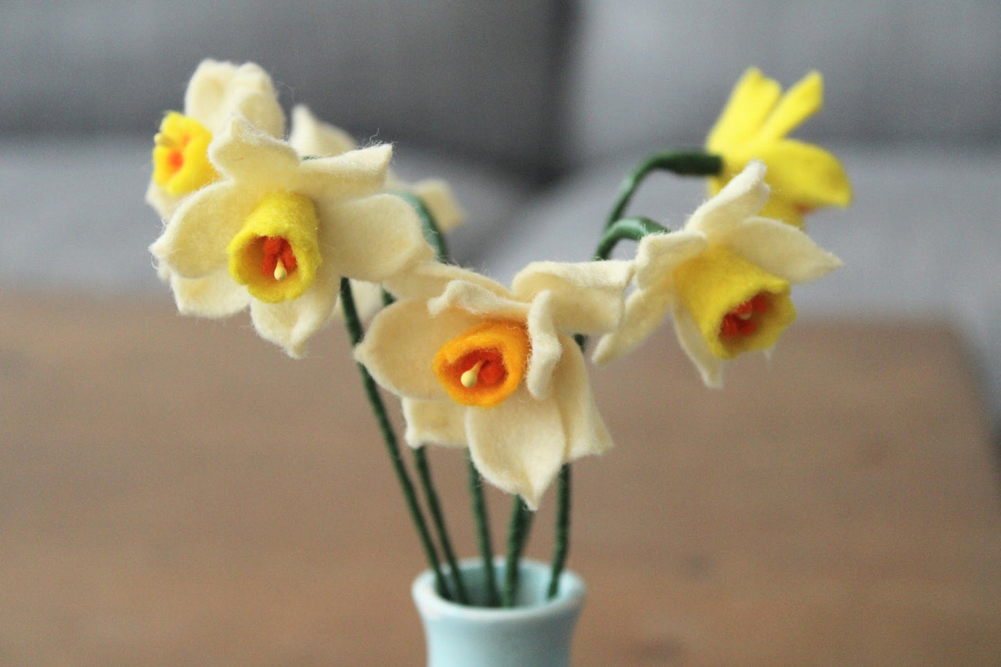 Handgemaakt boeketje met 6 mini Narcisjes in de kleuren wit, geel en donkergeel in een blauw vintage keramieken vaasje op een houten ondergrond
