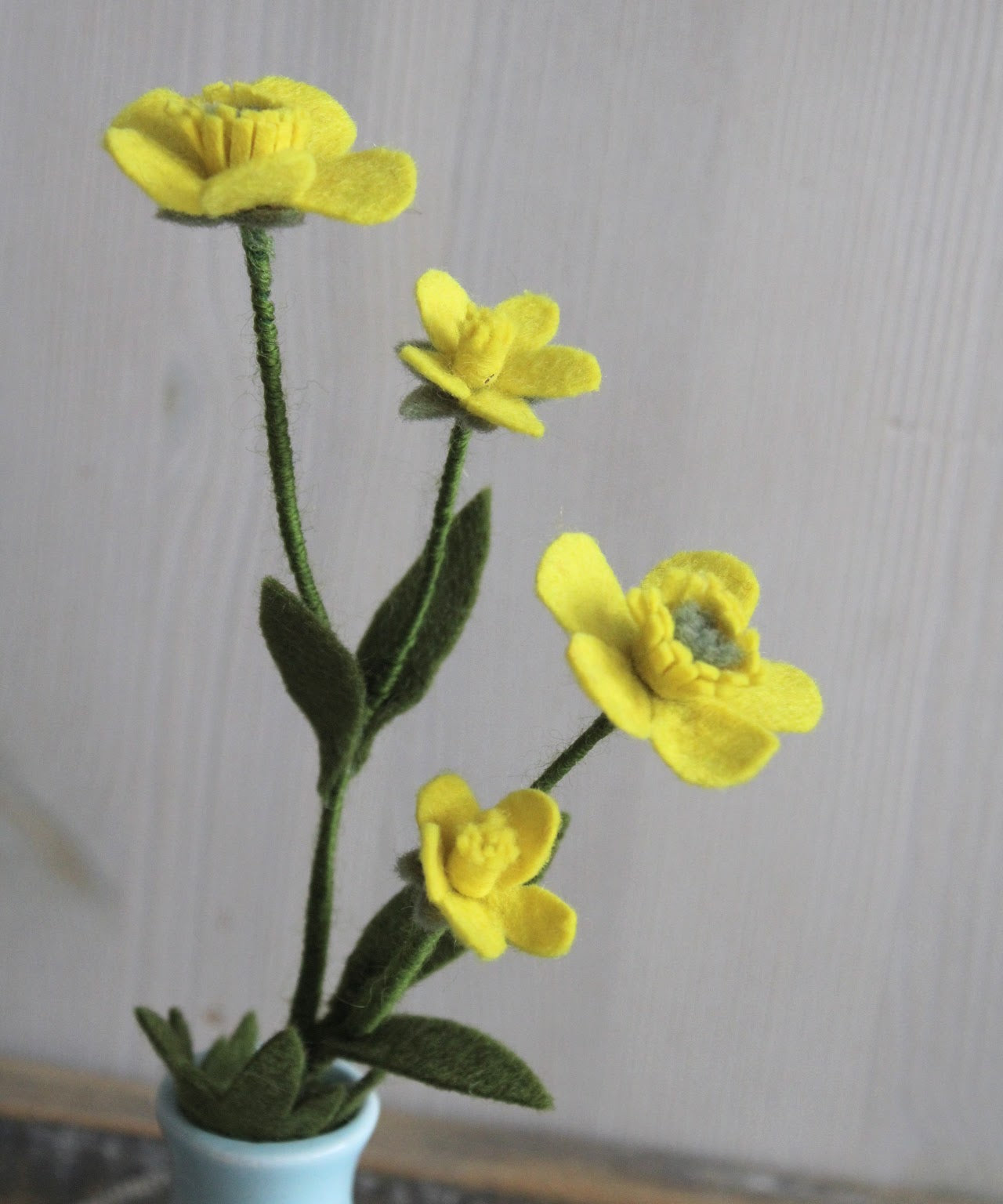 Close-up Vilten gele boterbloem met 4 bloemetjes en blaadjes als decoratie thuis met een lichte achtergrond