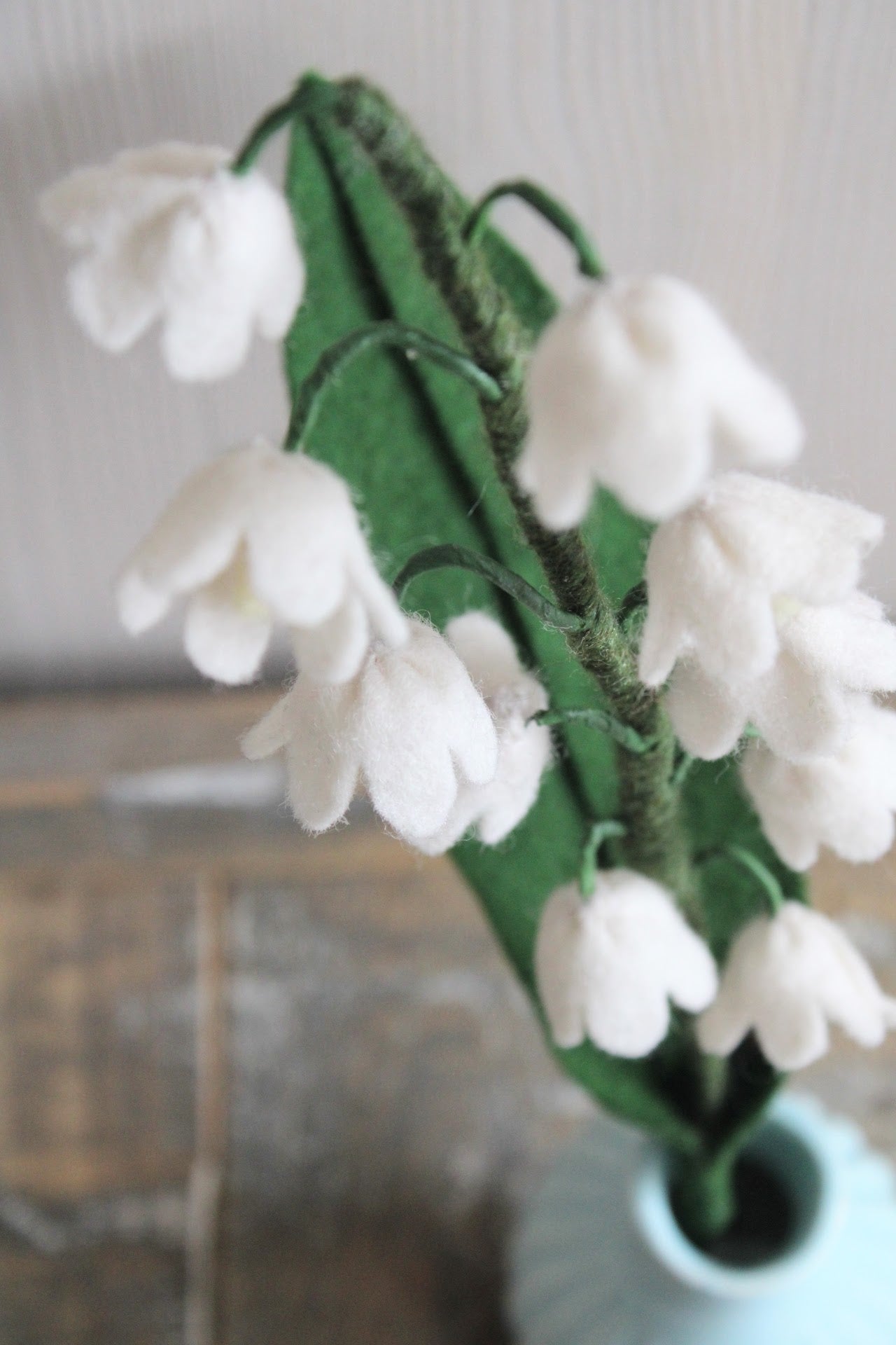 Close-up van boven van Handgemaakt lelietje-van-dalen van vilt met delicate witte bloemetjes en steel met wol bekleed