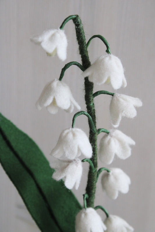 Closeup Handgemaakt lelietje-van-dalen van vilt met delicate witte bloemetjes en steel met wol bekleed