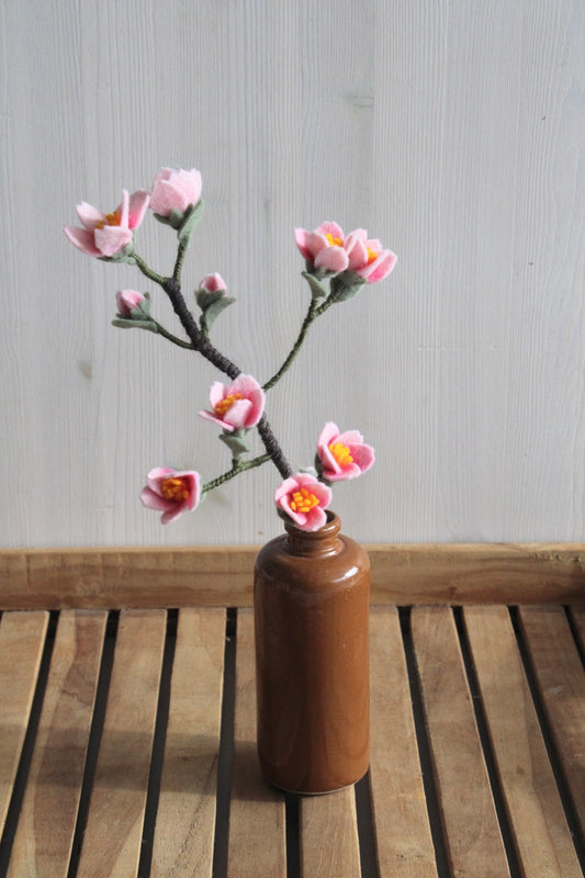 Handgemaakte kersenbloesemtak van vilt, ook wel bekend als Sakura,11 roze bloemen staat ter decoratie in jeneverfles op houten ondergrond