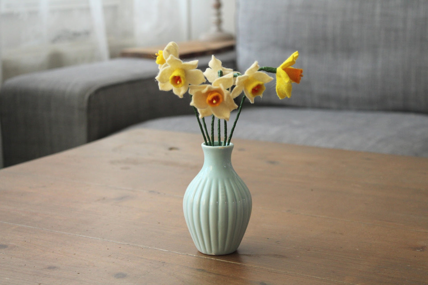 Handgemaakt boeketje met 6 mini Narcisjes in de kleuren wit, geel en donkergeel in een blauw vintage keramieken vaasje op een houten ondergrond