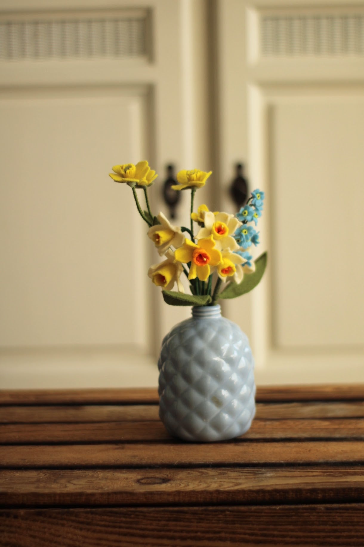 Handgemaakt boeketje met 6 mini Narcisjes, gele boterbloem,blauw vergeet me nietje in een blauw vintage keramieken vaasje op een houten ondergrond