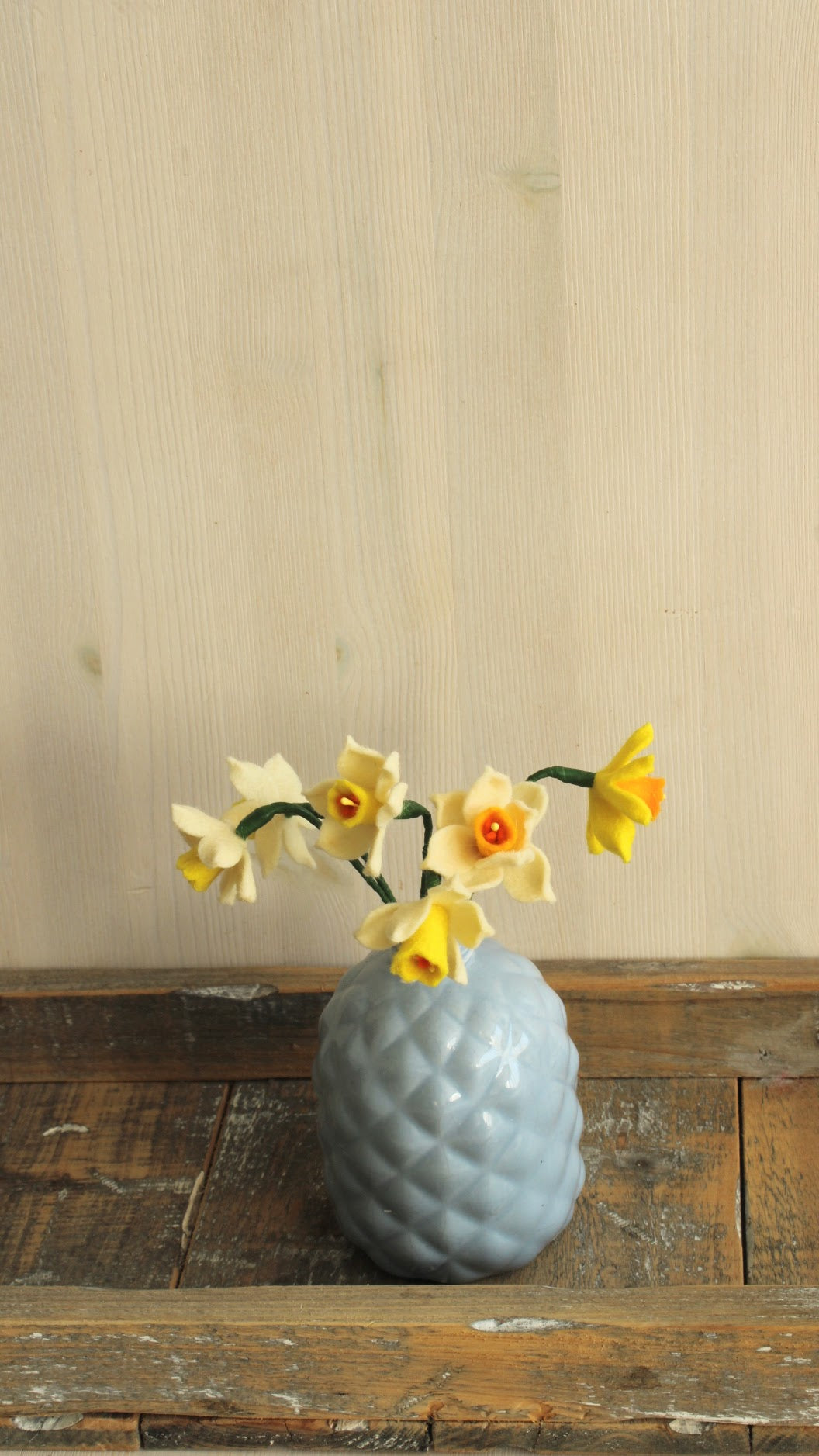 Handgemaakt boeketje met 6 mini Narcisjes in de kleuren wit, geel en donkergeel in een blauw/grijs keramieken vaasje op een houten ondergrond