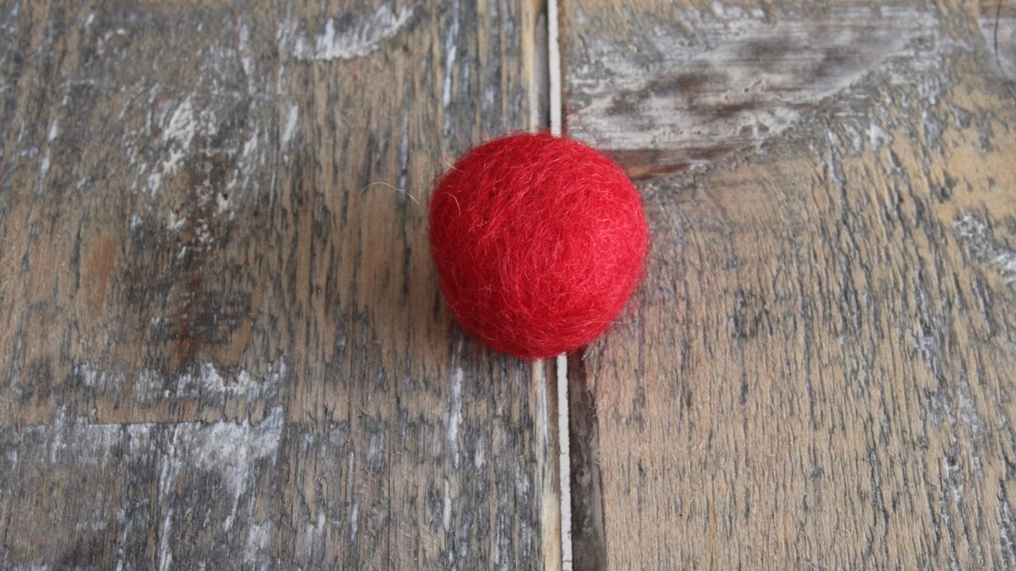 rood viltballetje op een rustiek houten oppervlak. kan gebruikt worden voor hart van viltbloemen of als knutselproject