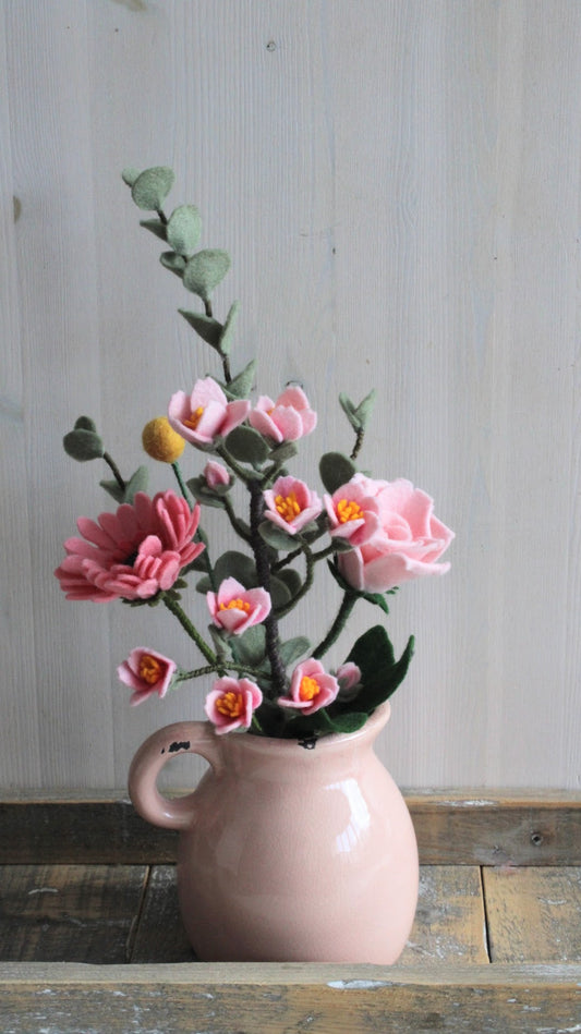 Roze kan met handgemaakte vilten bloemenboeket met daarin kersenbloesem (sakura), roze roos, roze gerbera, gele craspedia en dubbele eucalyptus tak