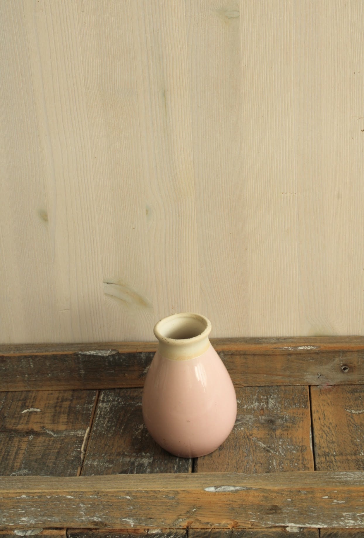 Roze vaasje geschikt voor viltbloemen met een smalle opening op een houten ondergrond