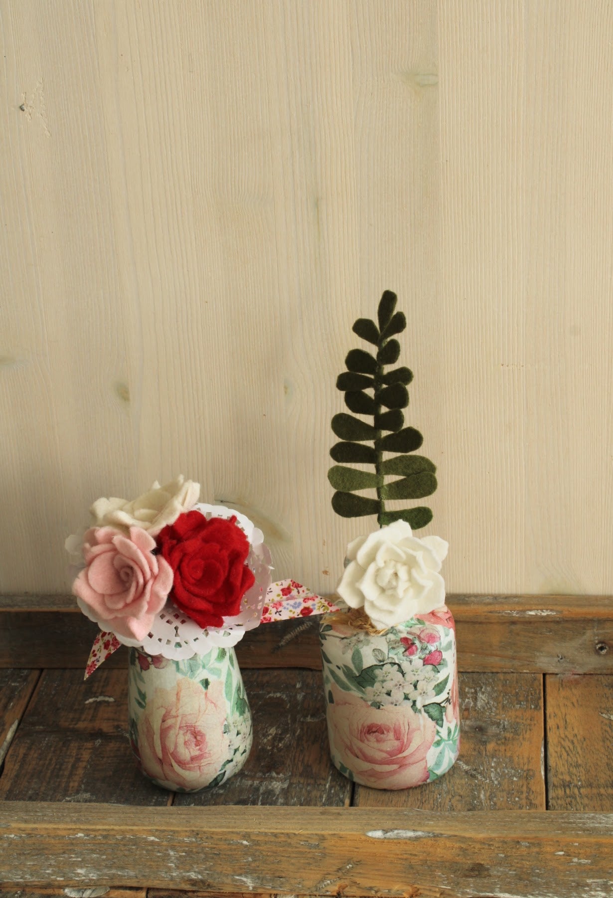 twee gebloemde vaasjes met biedermeiertje van roosjes en witte bloem met groen blad op een rustieke houten ondergrond