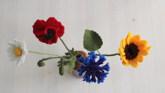 close-up van boven van Vilten bloemen veldboeket als decoratie. Handgemaakte zonnebloem, korenbloem, klaproos en margriet in bruine vaas op een houten achtergrond.