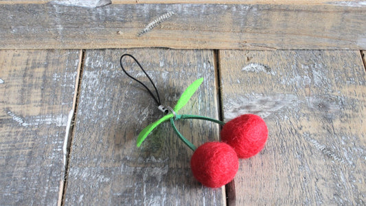 Handgemaakte rode vilten kersen sleutelhanger met groene vilten blaadjes, klaar om te worden bevestigd aan een sleutelbos of tas.