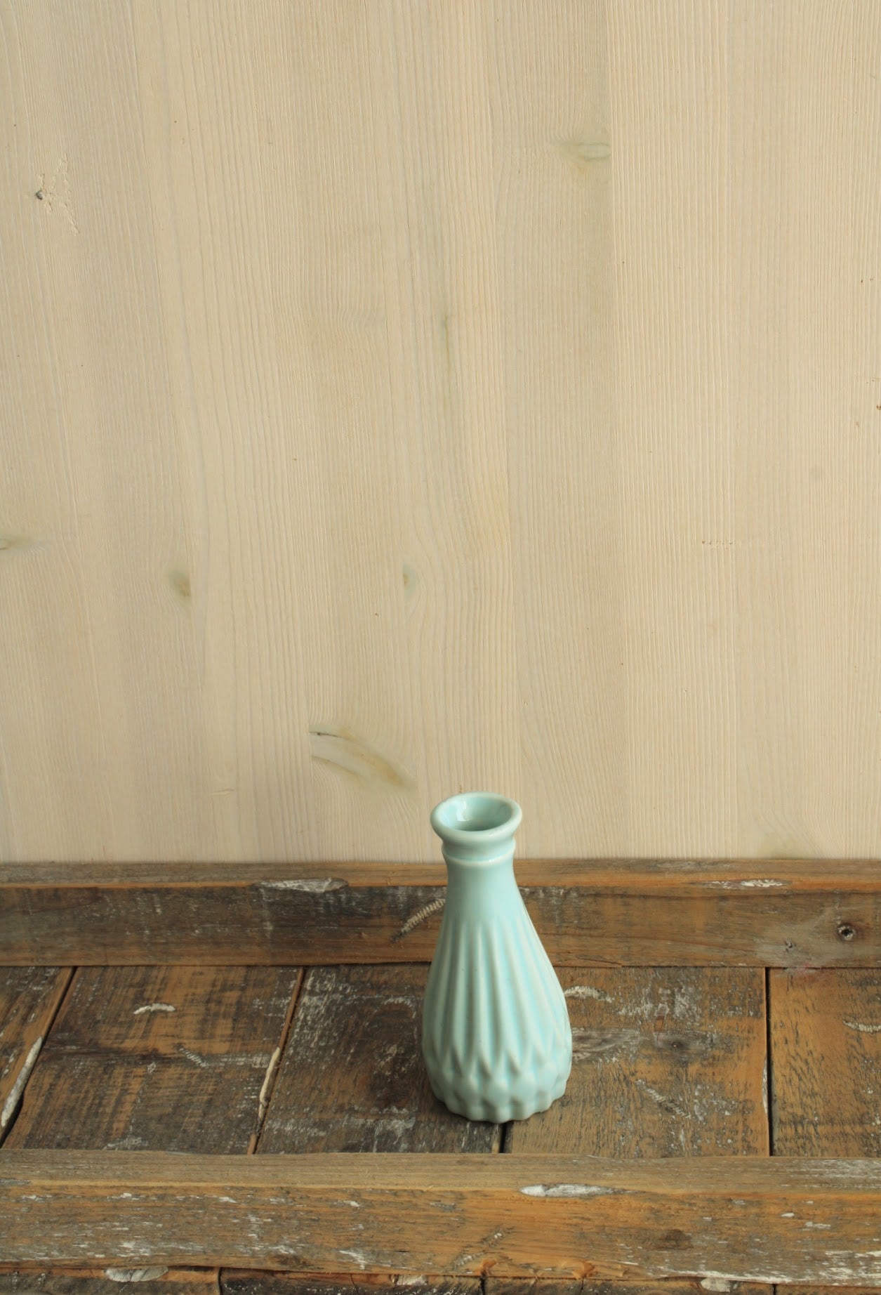 Blauw vintage vaasje, geribbeld en leuk voor kleine viltbloemen op een houten rustieke plank