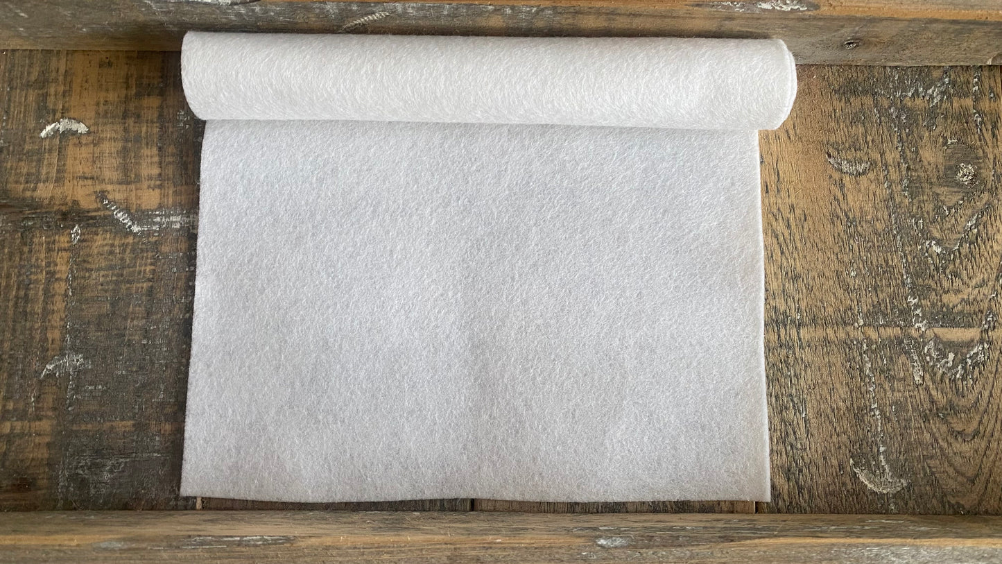 Rolletje wolvilt in de kleur wit nummer 42 op een houten ondergrond voor het maken van viltbloemen, zoals vilten roos, vilten anemoon, vilten pioenroos, hortensia van vilt