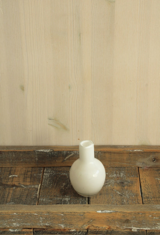 Bolvormig wit glazen vaasje perfect voor kleine viltbloemen op een houten ondergrond
