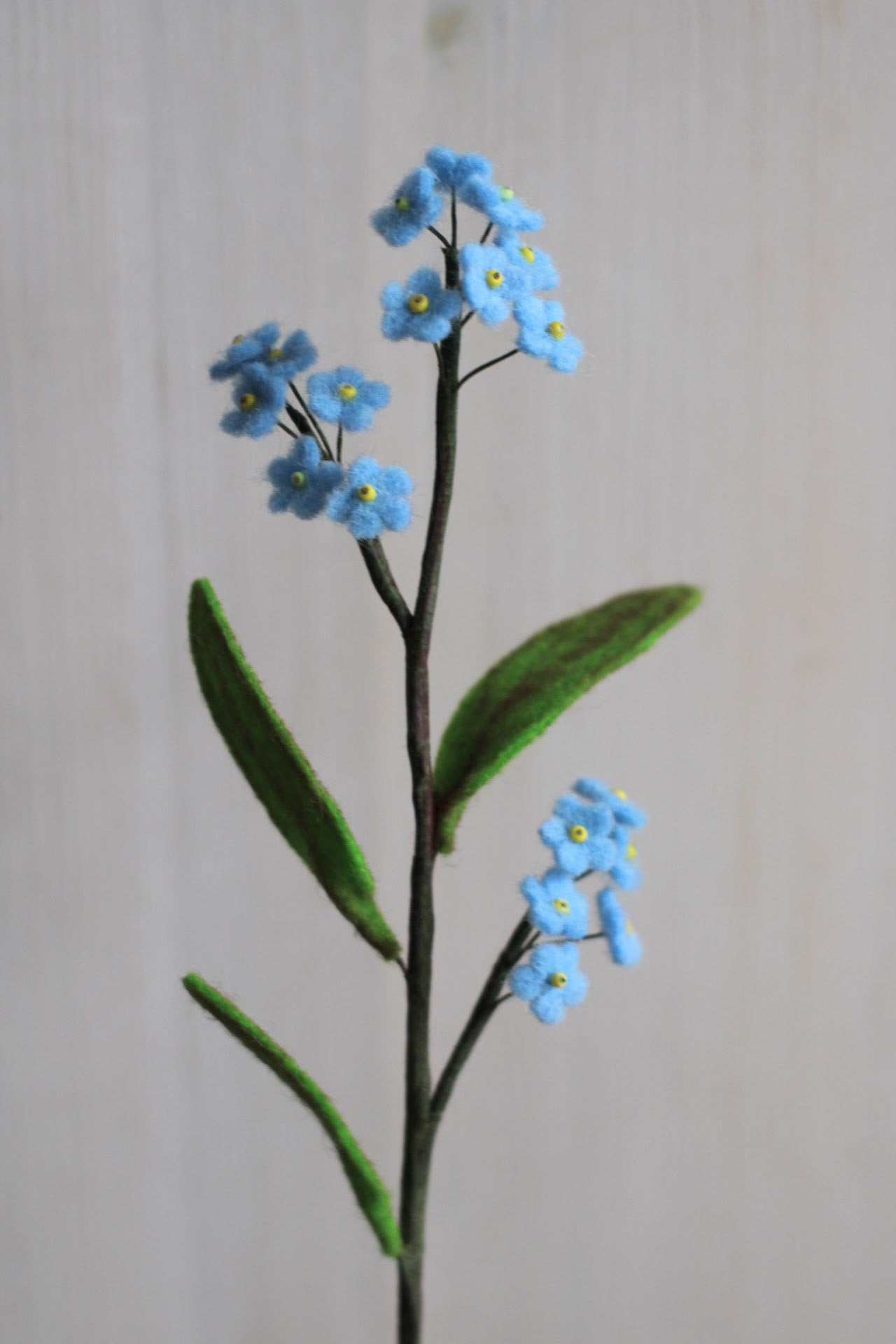 handgemaakt vergeet me nietje van 100% wolvilt met kleine blauwe bloemetjes en groene blaadjes