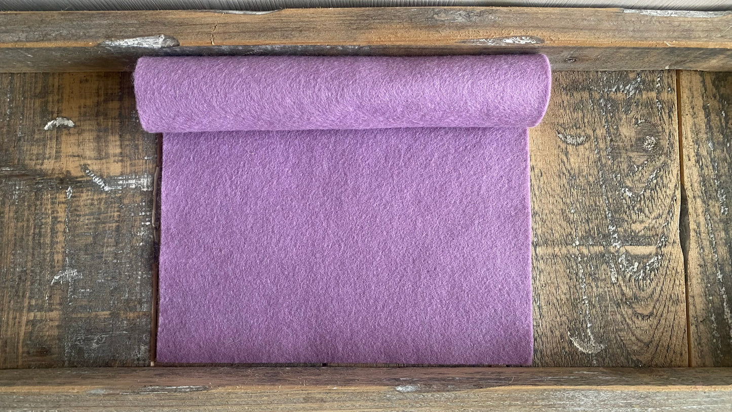 Rolletje wolvilt in de kleur rood lila nummer v531 op een houten ondergrond voor het maken van viltbloemen, zoals vilten roos, vilten anemoon, vilten lavendel, hortensia van vilt