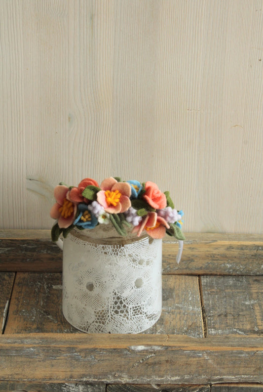Haarband met viltbloemen op een kanten glaasje op een rustieke houten ondergrond