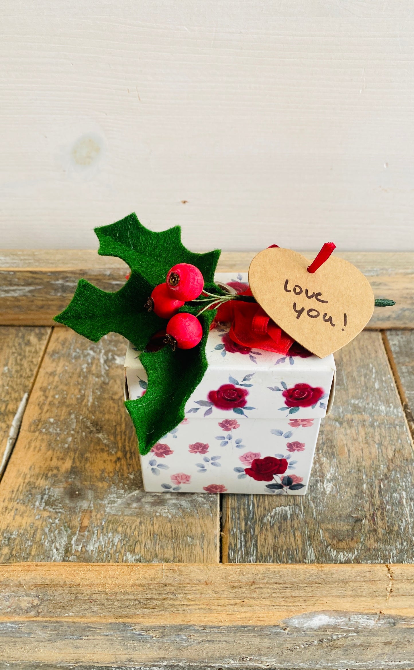 handgemaakt hulsttakje van vilt met rode bessen van hout als versiering op een cadeautje gemaakt tijdens de kerstworkshop in uithoorn