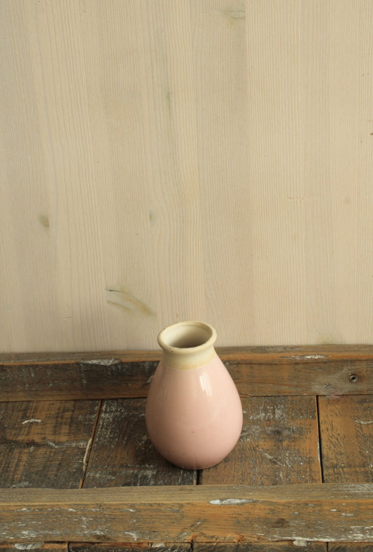 Roze vaasje geschikt voor viltbloemen met een smalle opening op een houten ondergrond
