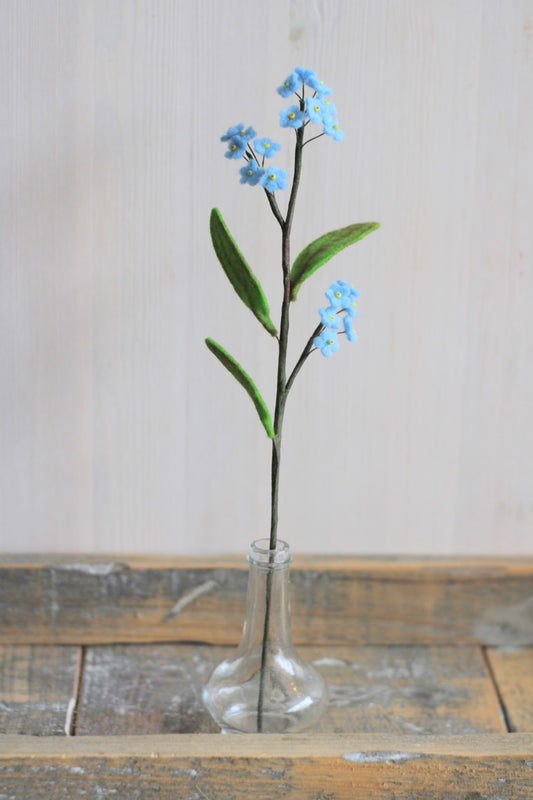 handgemaakt vergeet-me-nietje van vilt met drie trosjes kleine blauwe bloemetjes en drie groen blaadjes