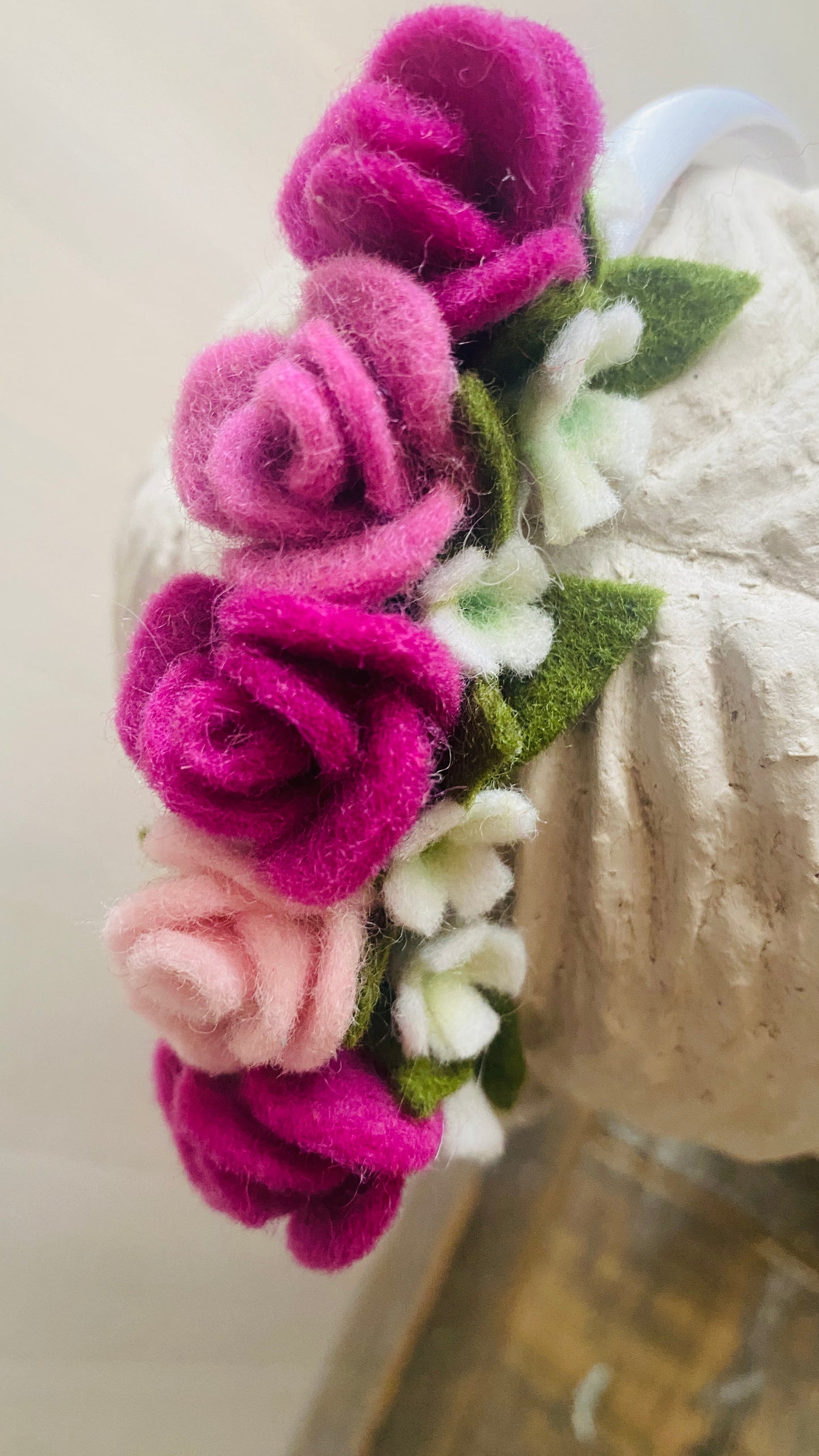 closeup van haarband met handgemaakte viltbloemen rozen en gipskruid
